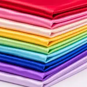 Tela de raso en varios colores doblada con acabado satinado y brillo suave, ideal para confección y decoración