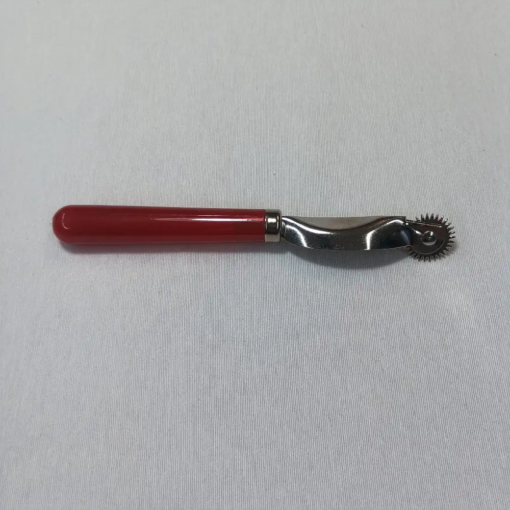 "Rueda de marcar para costura con mango rojo y cabeza metálica dentada, herramienta de sastrería utilizada para transferir patrones sobre tela."