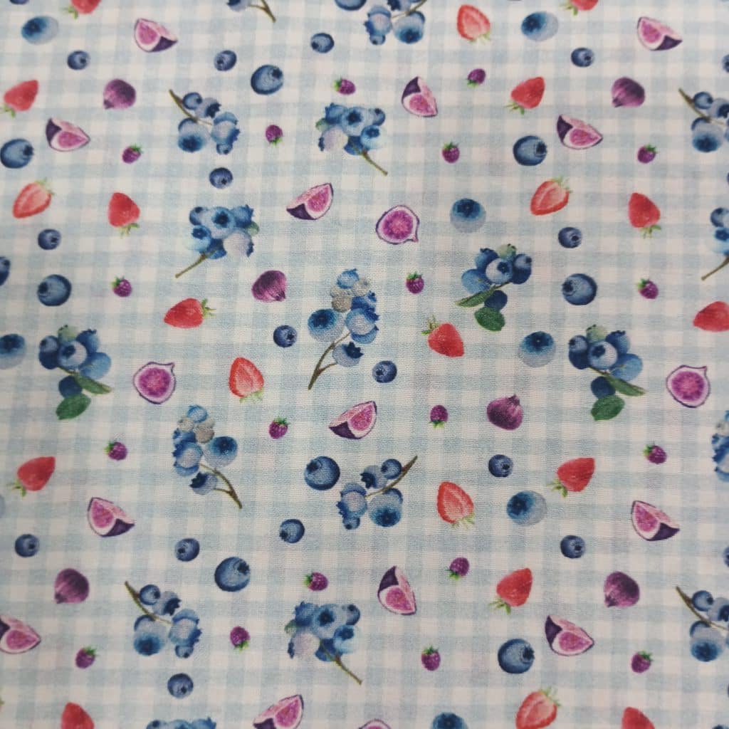 Tela de algodon 100% con estampado de frutas de temporada de verano, como arandanos, fresas, higos. El fondo del tejido es a cuadritos en un vichy muy clarito azul y blanco. Su textura es muy suave.