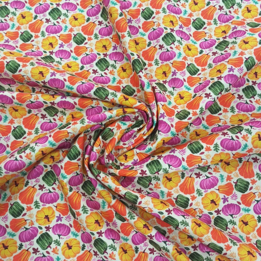 Algodón fondo crudo con estampados de calabazas de halloween en colores otoñales.