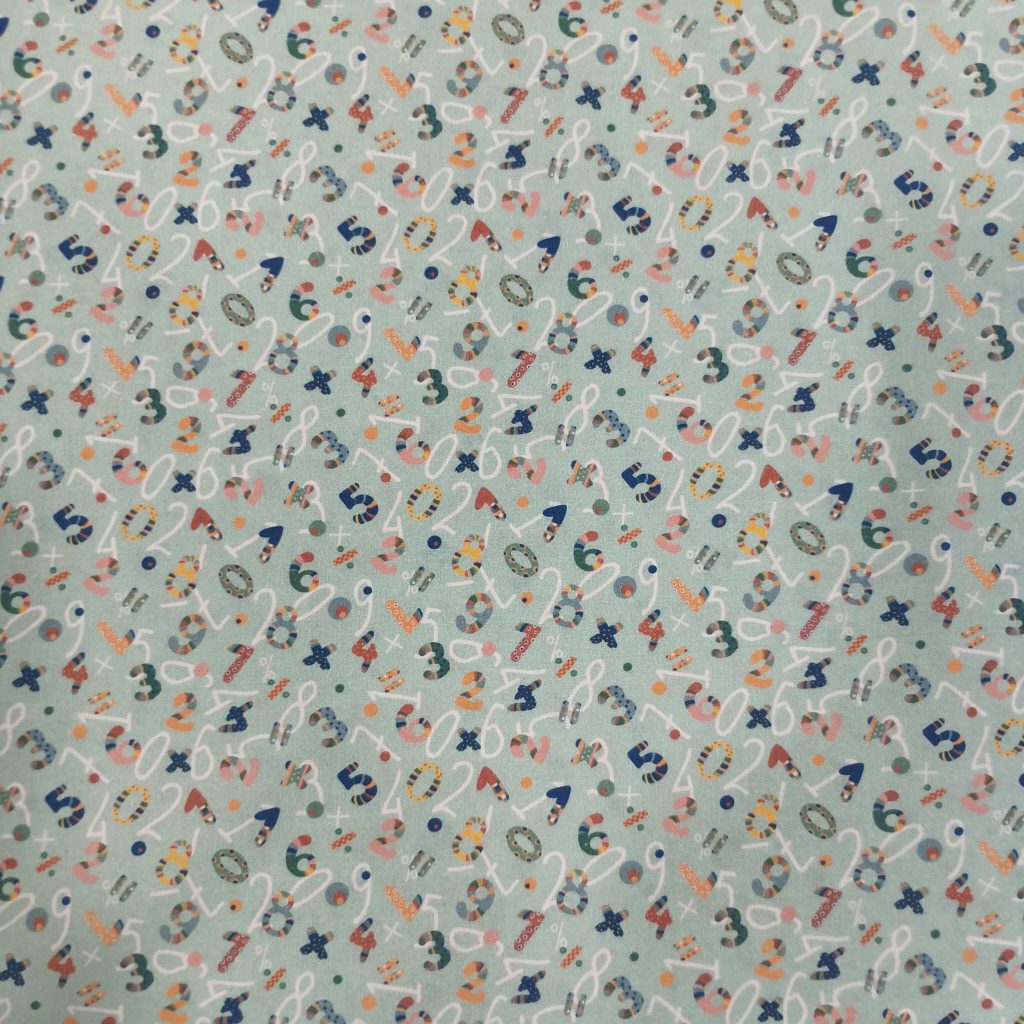 Tela de algodón con estampado colorido de números y símbolos, ideal para proyectos infantiles, educativos o creativos.