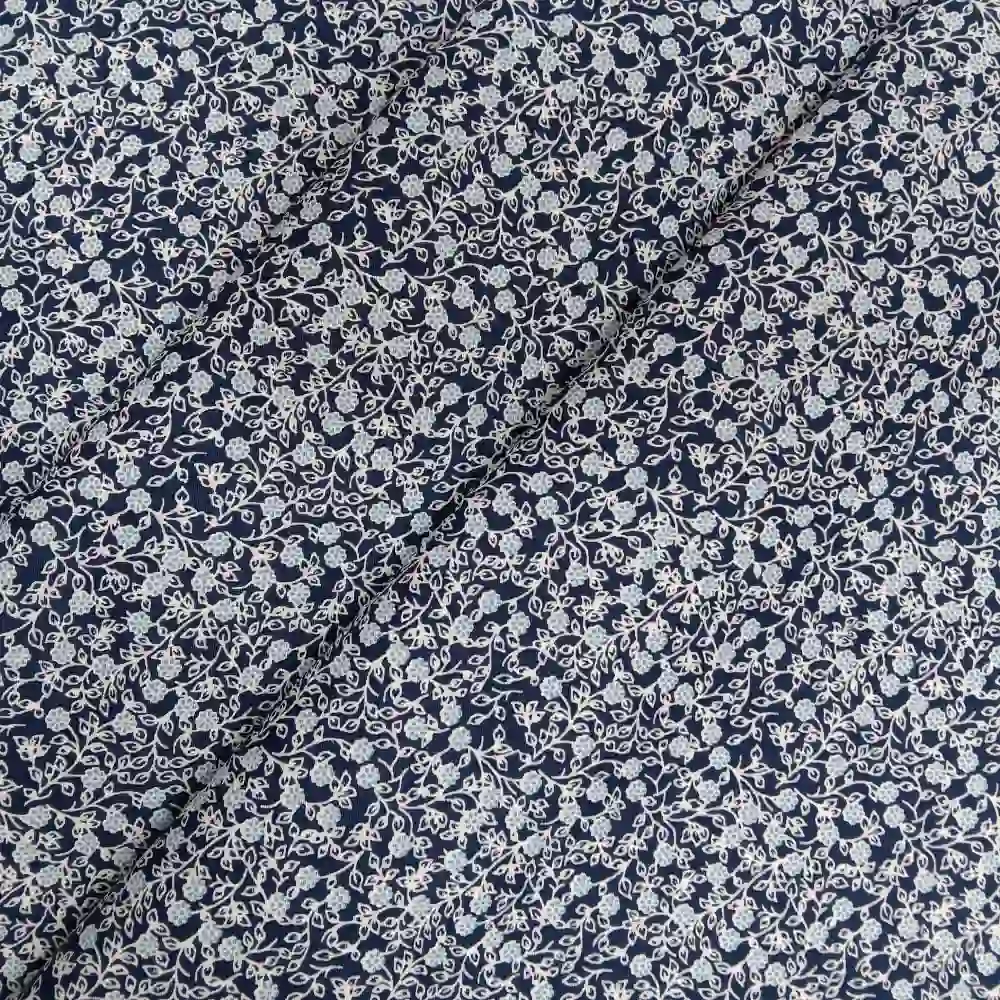 Tela de algodón estampada con flores pequeñas sobre fondo azul marino, ideal para confección, patchwork y decoración.