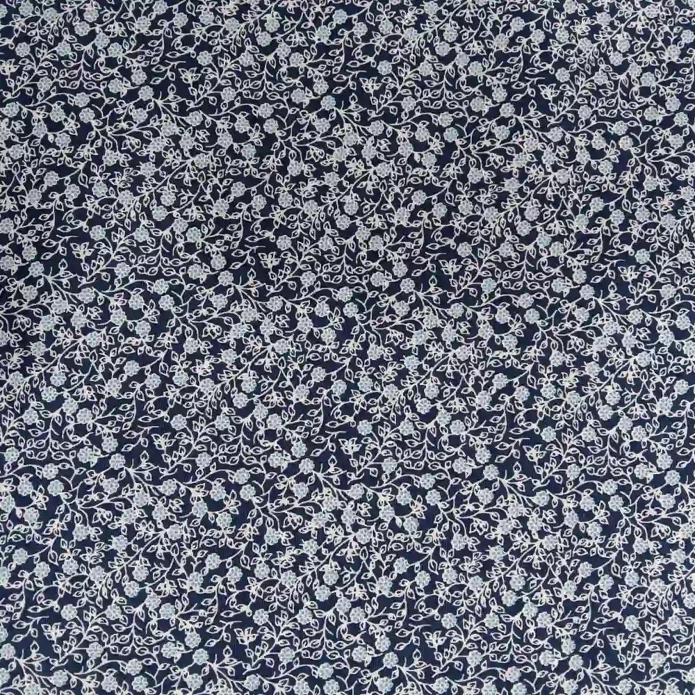 Tela de algodón estampada con flores pequeñas sobre fondo azul marino, ideal para confección, patchwork y decoración.