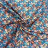 Tela de algodón estampada con flores de colores sobre fondo azul, perfecta para confección, patchwork y decoración.