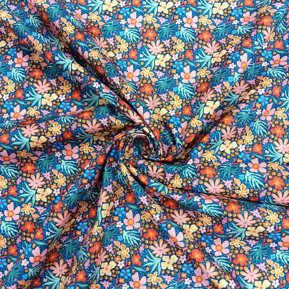 Tela de algodón estampada con flores de colores sobre fondo azul, perfecta para confección, patchwork y decoración.