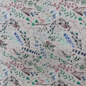 Tela de algodón estampado con ramas de flores en tonos azules, verdes y lilas sobre fondo beige natural.