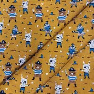 Tela de algodón infantil estampada con piratas sobre fondo mostaza, ideal para confección, decoración y manualidades infantiles.