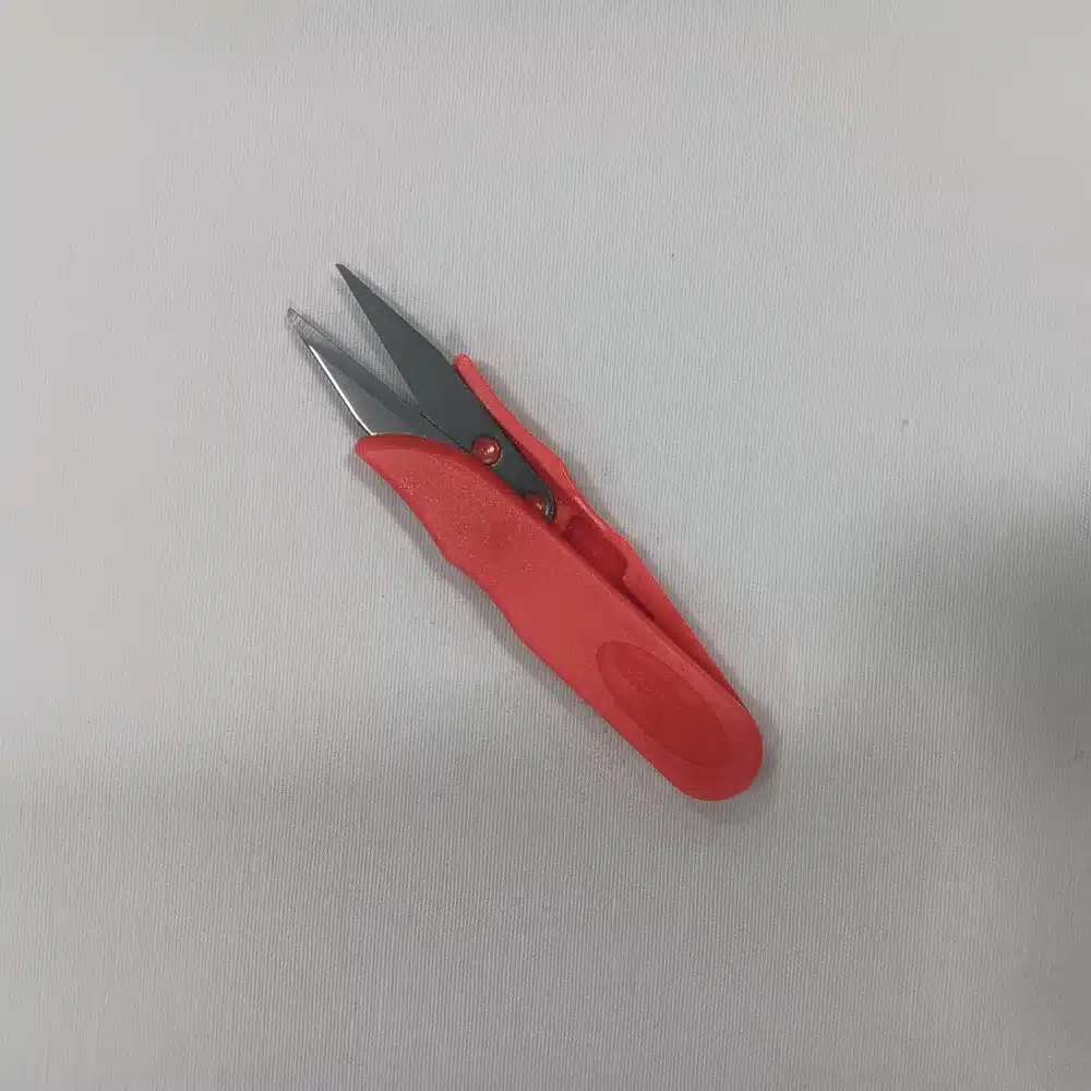 Tijera corta-hilo compacta con hojas de acero inoxidable y cuerpo en color rojo. Ligera y perfecta para cortes rápidos.