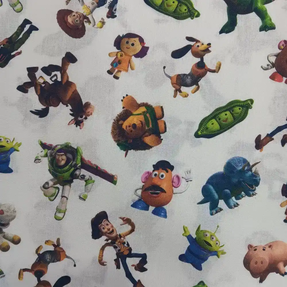 Tela de algodón con licencia Disney Toy Story con personajes como Woody, Buzz Lightyear, Jessie y los marcianitos sobre fondo claro.