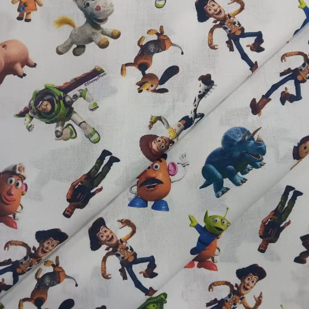 Tela de algodón con licencia Disney Toy Story con personajes como Woody, Buzz Lightyear, Jessie y los marcianitos sobre fondo claro.