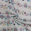 tela-algodon-licencia-doraemon-3 Tela de algodón con estampado de licencia Doraemon, mostrando al personaje azul sonriente junto a elementos amarillos y rojos sobre un fondo blanco.