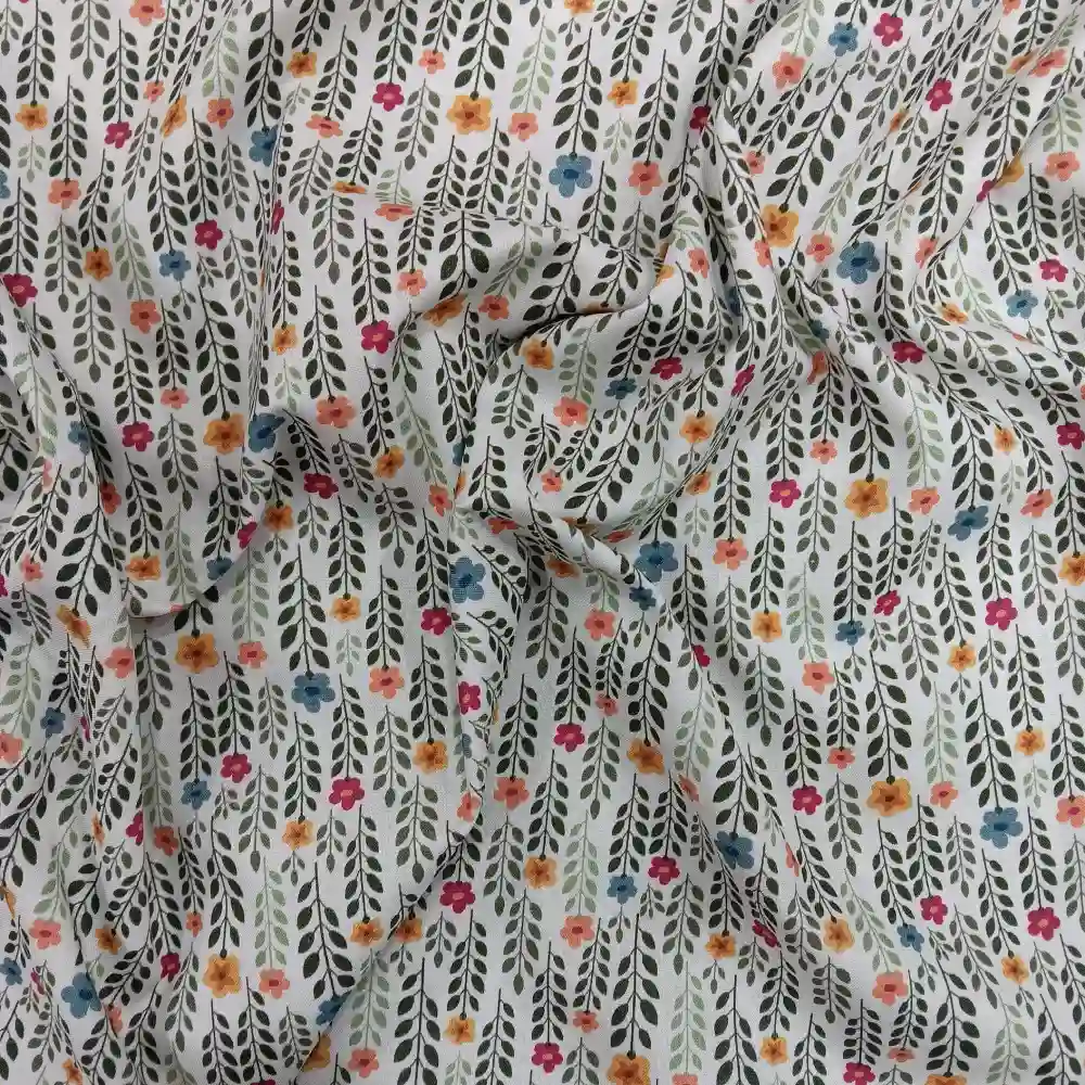 Tela de algodón estampado con flores pequeñas de colores y tallos verdes distribuidos sobre fondo claro, con diseño floral repetido.