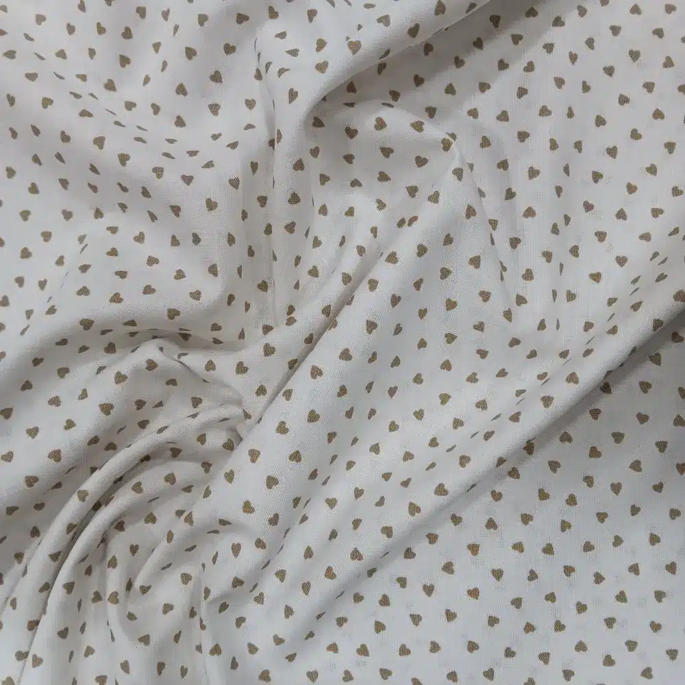 Tela de algodón blanco con estampado de pequeños corazones beige