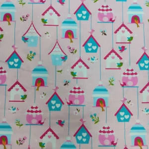 Tela de algodón con estampado infantil de casitas de pájaros y pequeños pájaros de colores sobre fondo rosa.