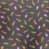 tela-algodon-cohetes-con-caritas-1 Tela de algodón con fondo oscuro y estampado repetido de pequeños cohetes de colores con caritas sonrientes y detalles de explosiones decorativas.