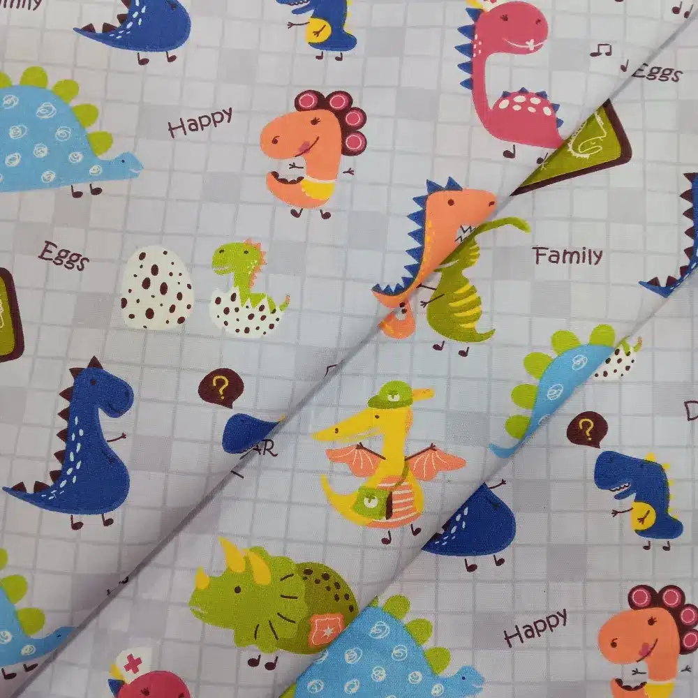 Tela de algodón con estampado infantil de dinosaurios de colores sobre fondo claro con dibujos y palabras decorativas