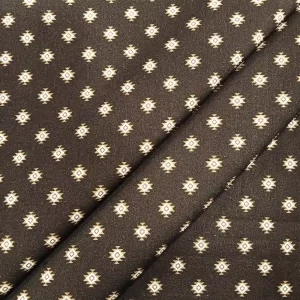 Tela de algodón estampado geométrico tribal con motivos étnicos sobre fondo oscuro.