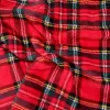 Primer plano de una tela coralina con estampado de cuadros escoceses en rojo, verde, azul y blanco, estilo clásico navideño."