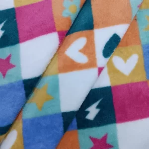 Primer plano de una tela coralina con cuadros multicolor decorados con corazones, estrellas y pequeños símbolos