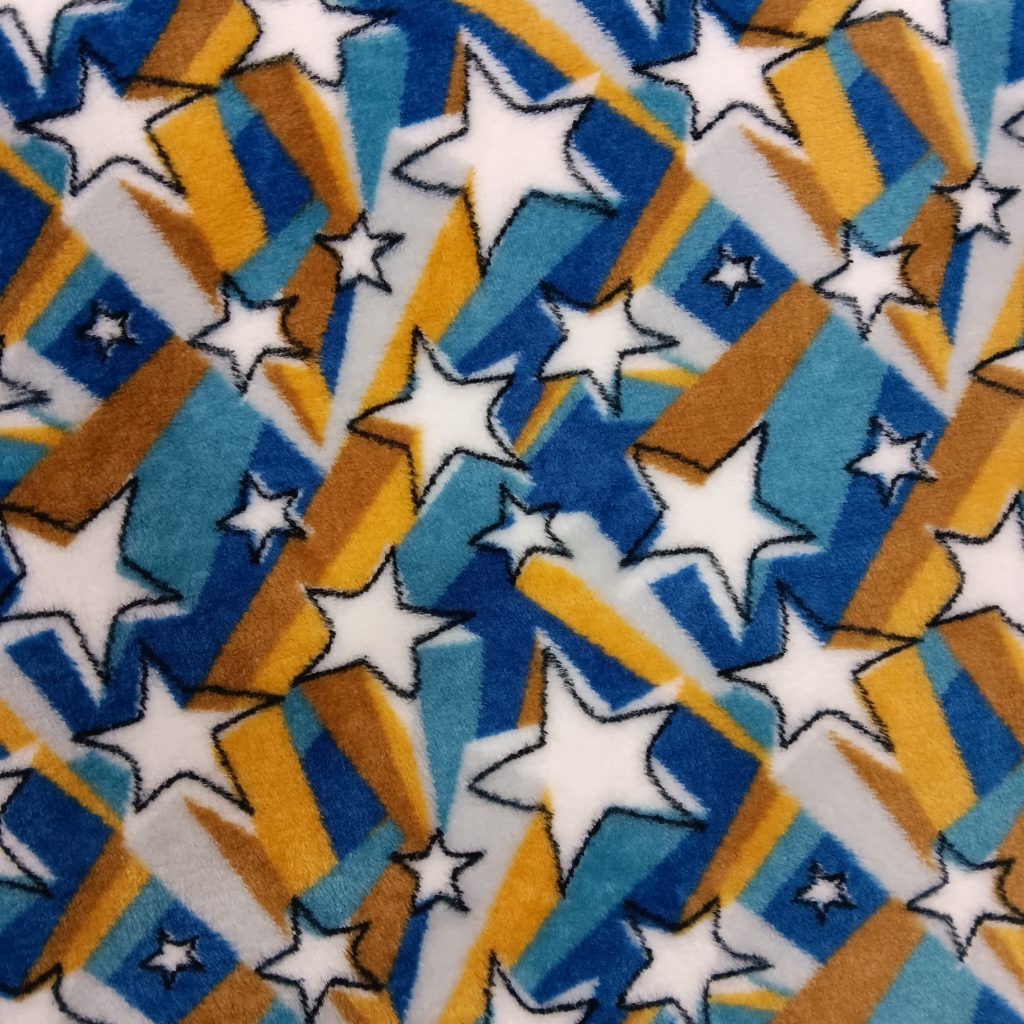 Primer plano de una tela coralina con estrellas blancas y franjas geométricas en azul, mostaza y marrón sobre fondo blanco.