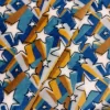Primer plano de una tela coralina con estrellas blancas y franjas geométricas en azul, mostaza y marrón sobre fondo blanco