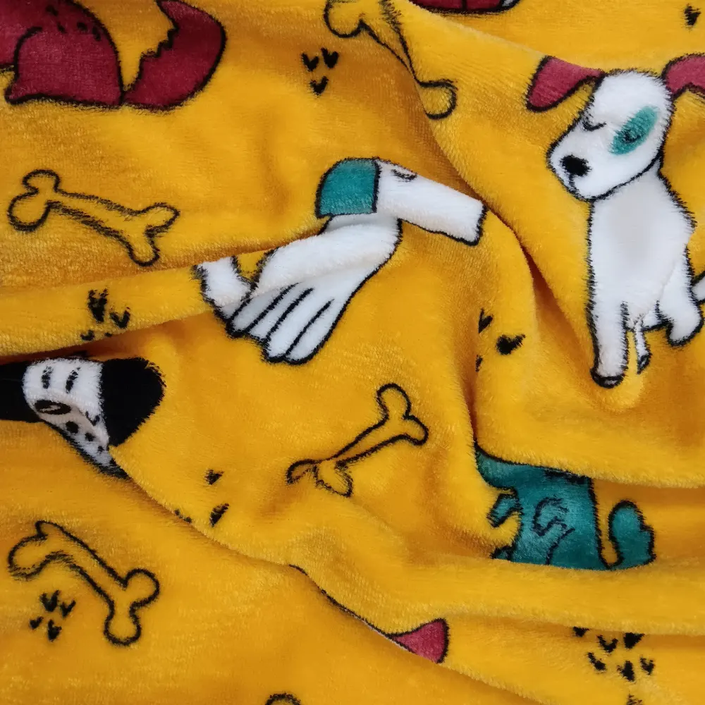 Primer plano de una tela coralina amarilla con dibujos infantiles de perritos, huesos y pequeñas huellas negras