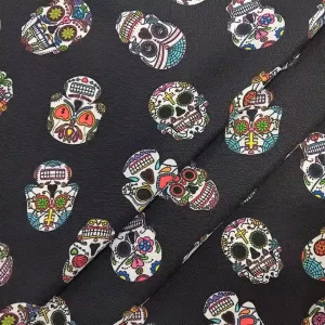Imagen de una tela de poliéster de fondo negro con un patrón repetido de calaveras mexicanas decoradas con colores vivos como rosa, verde, azul, amarillo y rojo.