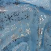 Tela de organza azul con estampado de copos de nieve plateados