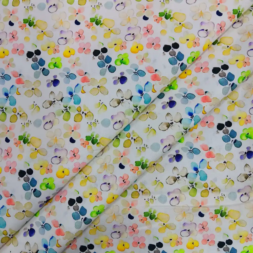Tela de algodón blanca con estampado floral multicolor estilo acuarela, con pequeñas flores en tonos suaves amarillo, rosa, verde, azul y lila repartidas por toda la superficie.