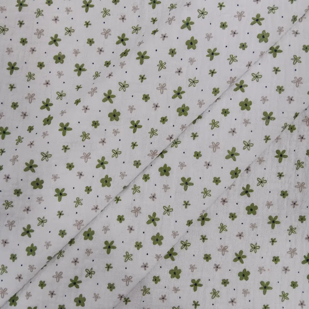 Muselina de algodón estampada con pequeñas flores verdes sobre fondo claro