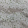 Muselina de algodón estampada con pequeñas flores verdes sobre fondo claro