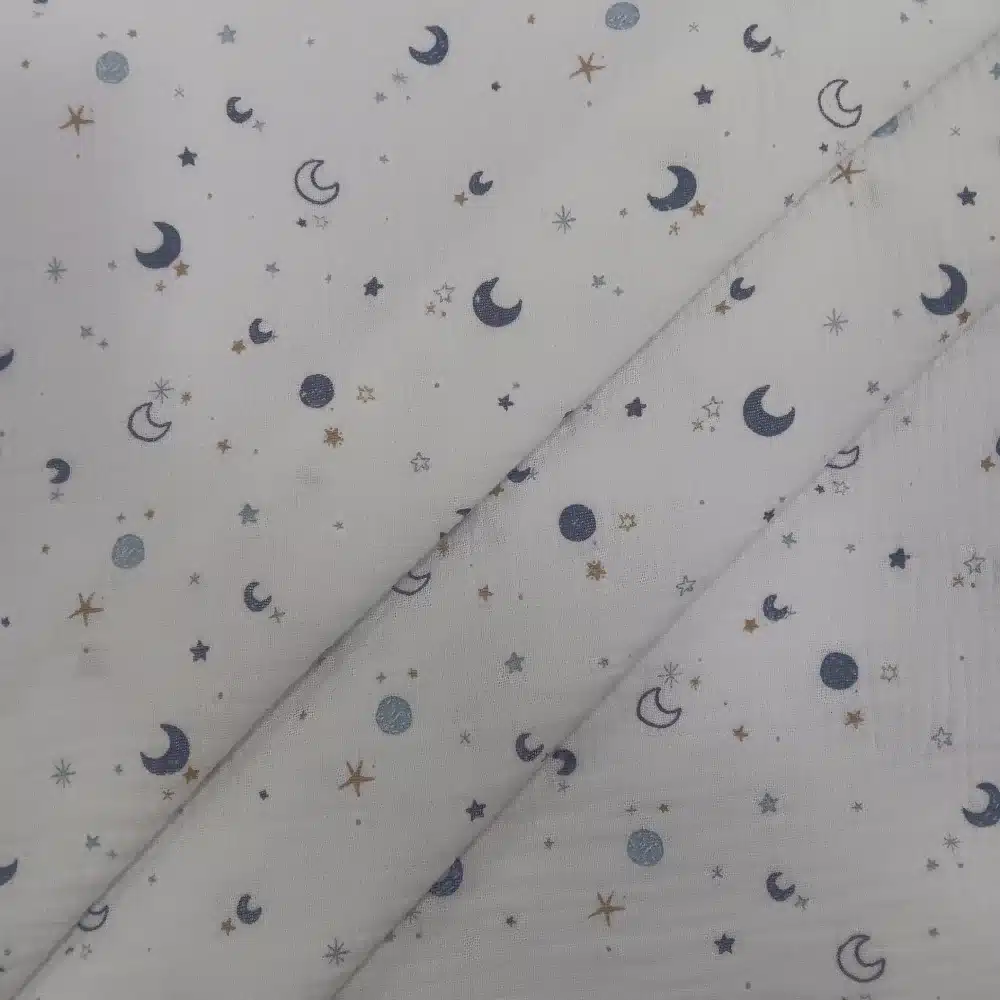 Muselina de algodón estampada con lunas y estrellas en tonos azules sobre fondo claro