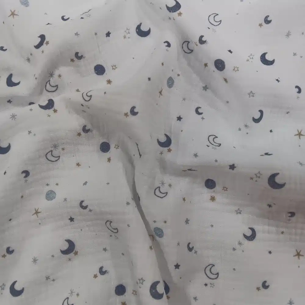 Muselina de algodón estampada con lunas y estrellas en tonos azules sobre fondo claro