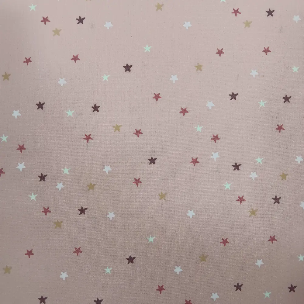 Tela de algodón rosa con estrellas pequeñas estampadas en varios colores