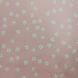 Tela de algodón rosa con flores blancas pequeñas estampadas sobre fondo rosa