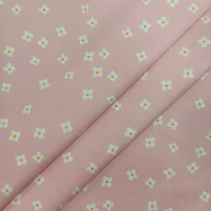 Tela de algodón rosa con flores blancas pequeñas estampadas sobre fondo rosa