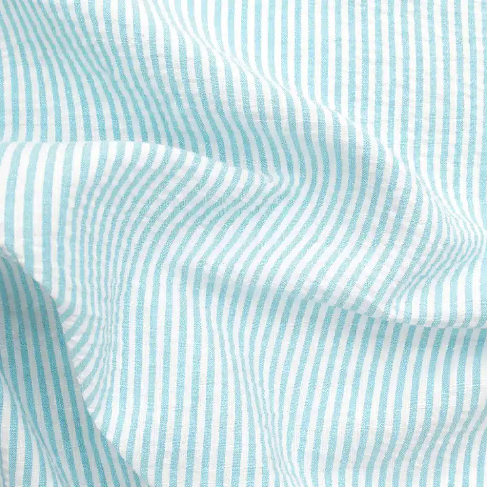 Tela seersucker de rayas finas en color azul con textura arrugada característica para confección de verano
