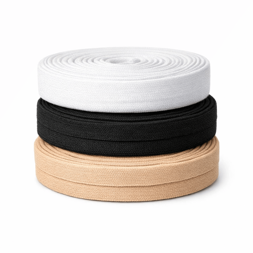 Tres rollos de cinta de bies de punto en colores blanco, negro y beige, apilados uno encima de otro sobre fondo blanco, mostrando su textura suave y elástica