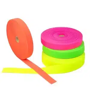Rollos de cinta de colores neón — naranja, rosa, verde y amarillo — colocados en grupo, con una cinta naranja extendida en primer plano