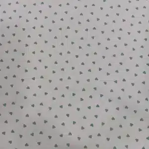 Tela de algodón blanca estampada con pequeños corazones verde mint distribuidos de forma uniforme.