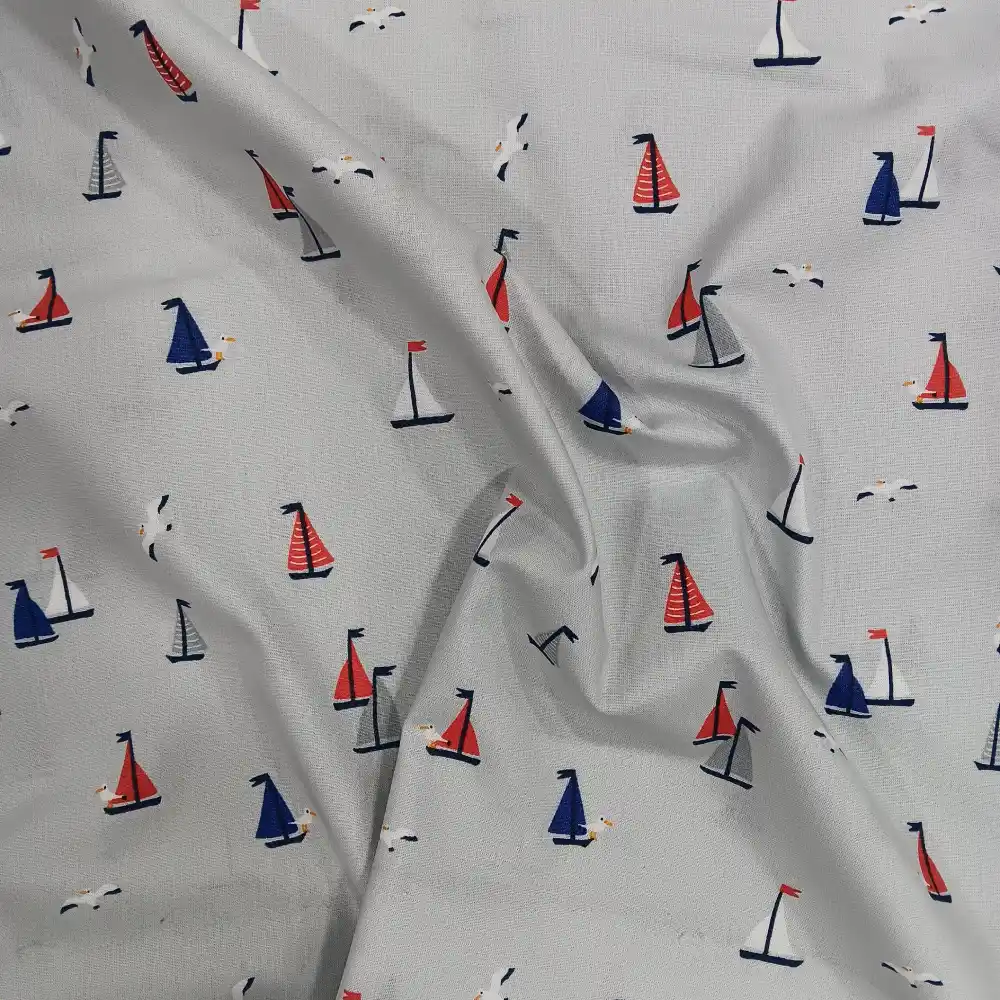 tela-algodon-estampada-barcos-vela-2 Tela de algodón estampada con pequeños barcos de vela y gaviotas en tonos azul, rojo y gris sobre fondo claro.
