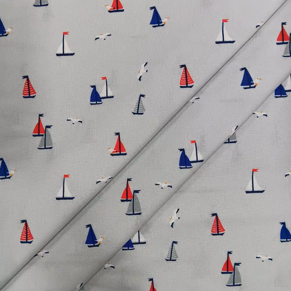 tela-algodon-estampada-barcos-veleros-2 Tela de algodón estampada con pequeños barcos de vela y gaviotas en tonos azul, rojo y gris sobre fondo claro.
