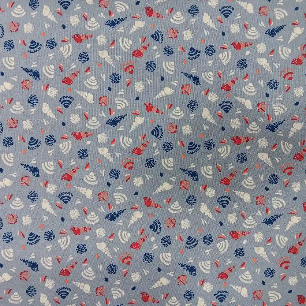 Tela de algodón estampada con caracolas marinas y conchas en tonos azul, coral y blanco sobre fondo azul claro.