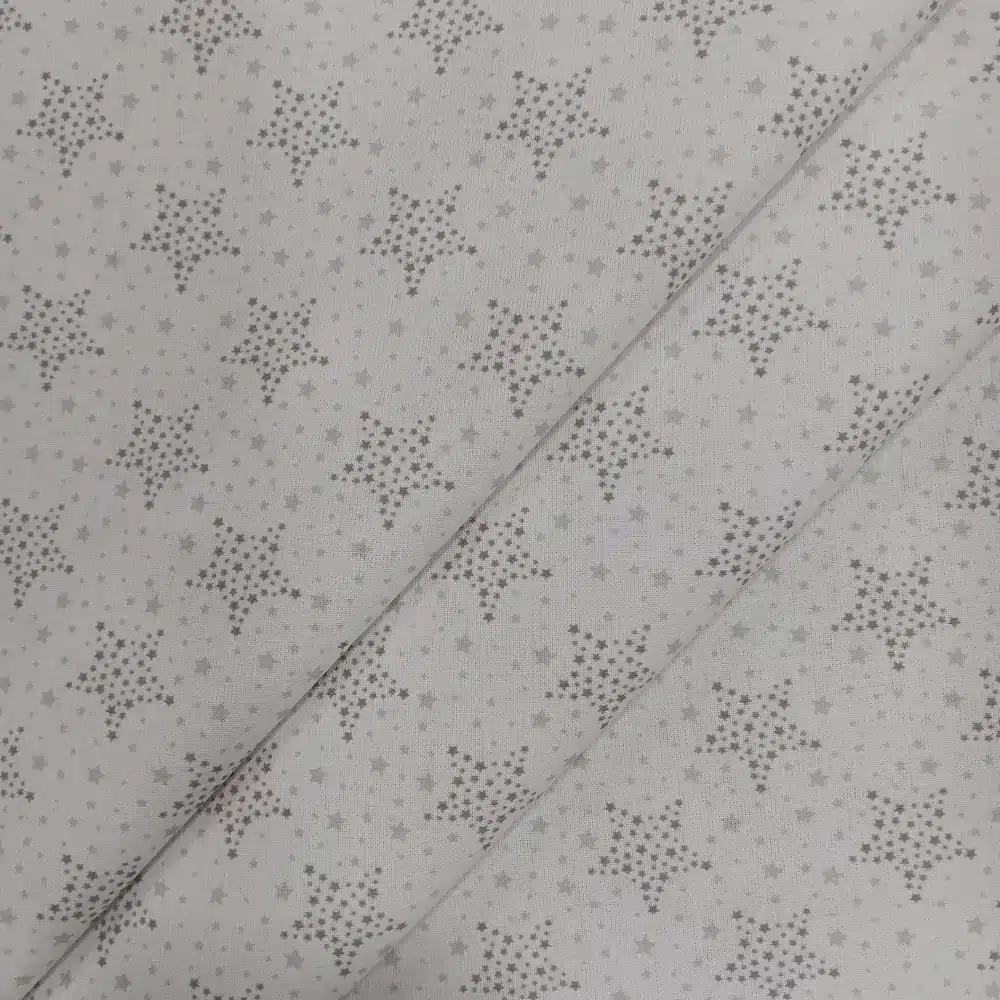 Tela de algodón blanca con estrellas punteadas grises y pequeñas estrellas distribuidas sobre fondo blanco.