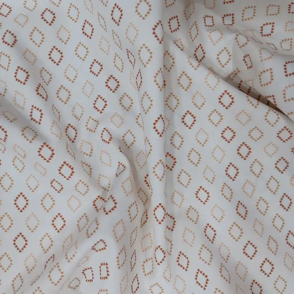 Tela de algodón blanca con estampado de rombos geométricos en tonos terracota y camel.