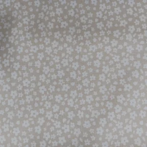 Tela de algodón estampada beige con pequeñas flores blancas distribuidas sobre fondo beige claro.