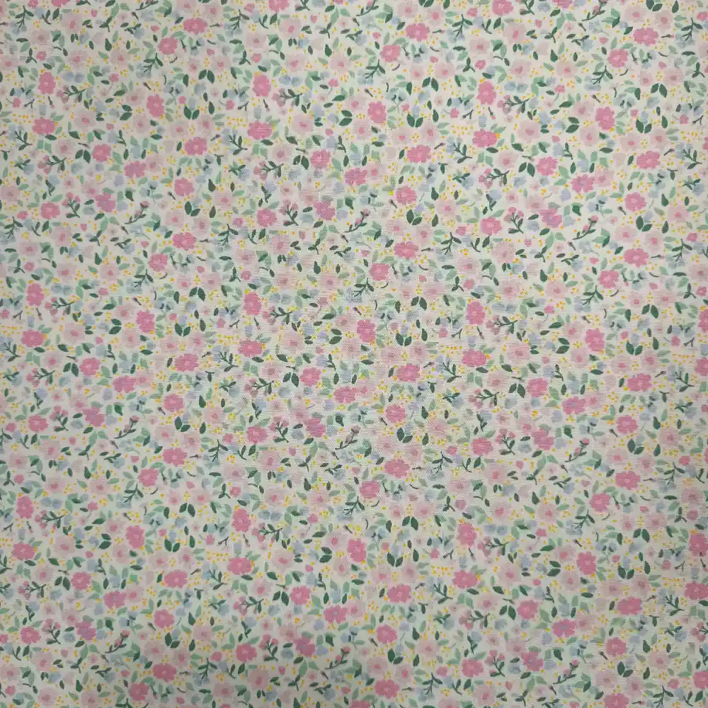 Tela de algodón blanca estampada con numerosas flores pequeñas en tonos rosas, hojas verdes y diminutos detalles amarillos, distribuidos por toda la superficie.