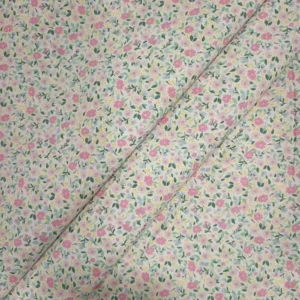 Tela de algodón blanca estampada con numerosas flores pequeñas en tonos rosas, hojas verdes y diminutos detalles amarillos, distribuidos por toda la superficie.
