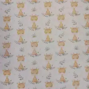 Tela de algodón estampada con jirafas sobre fondo claro, acompañadas de pequeñas hojas, ramas y motivos vegetales en tonos suaves.