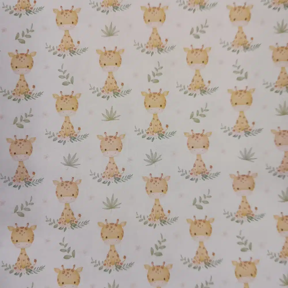 Tela de algodón estampada con jirafas sobre fondo claro, acompañadas de pequeñas hojas, ramas y motivos vegetales en tonos suaves.